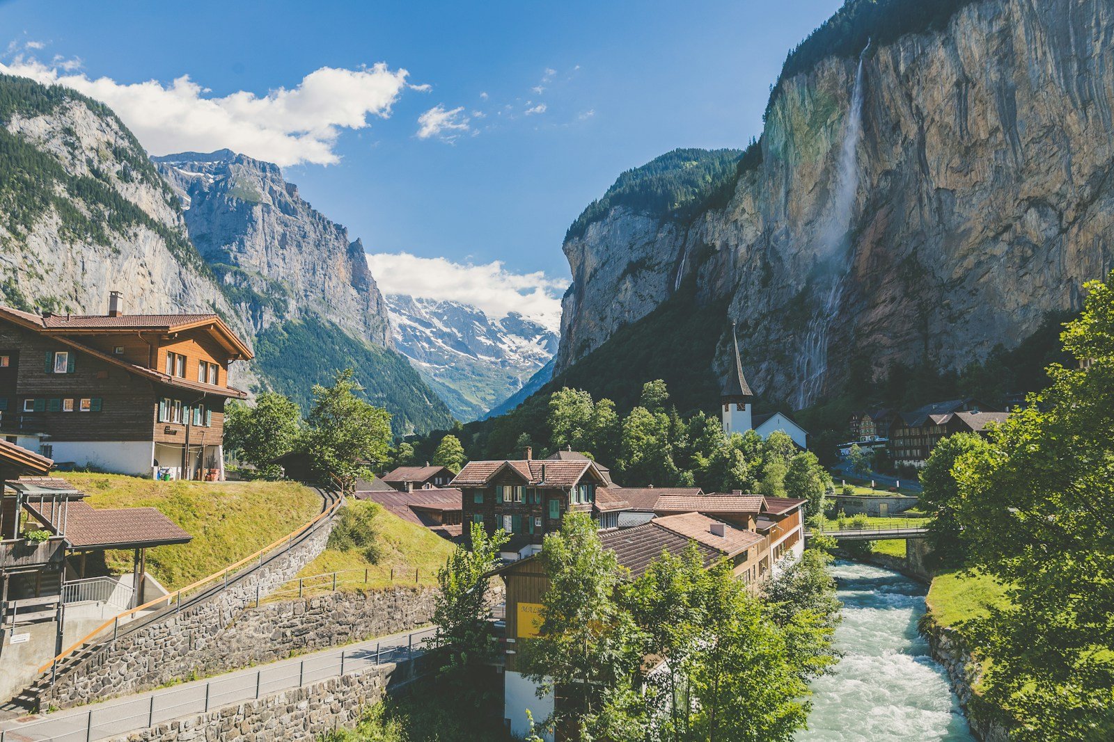 a river running through a valley with buildings and mountains